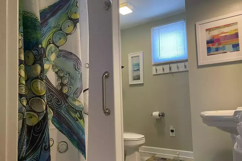 The bathroom features a walk-in shower, tiled floor and pedestal sink.
