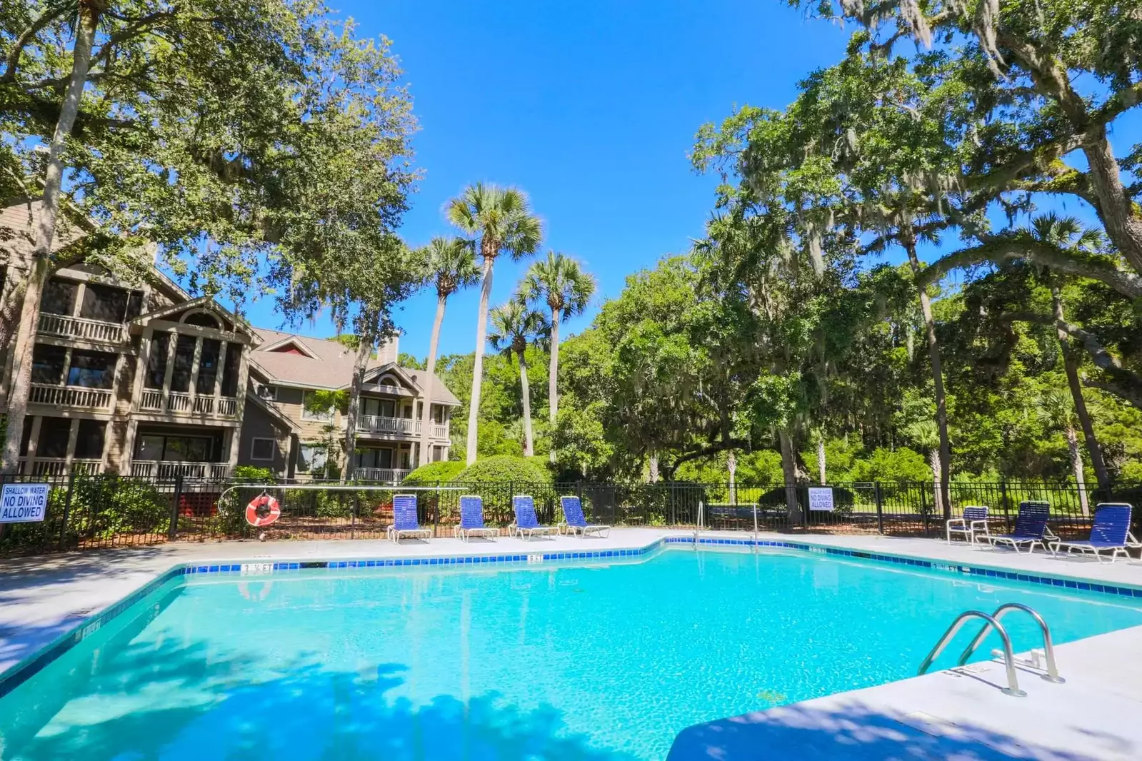 The community pool has lounge chairs, a dining table and bathrooms.