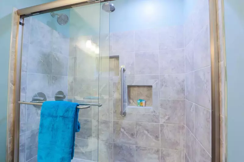 The tiled shower also has two rain showerheads and sliding glass doors.