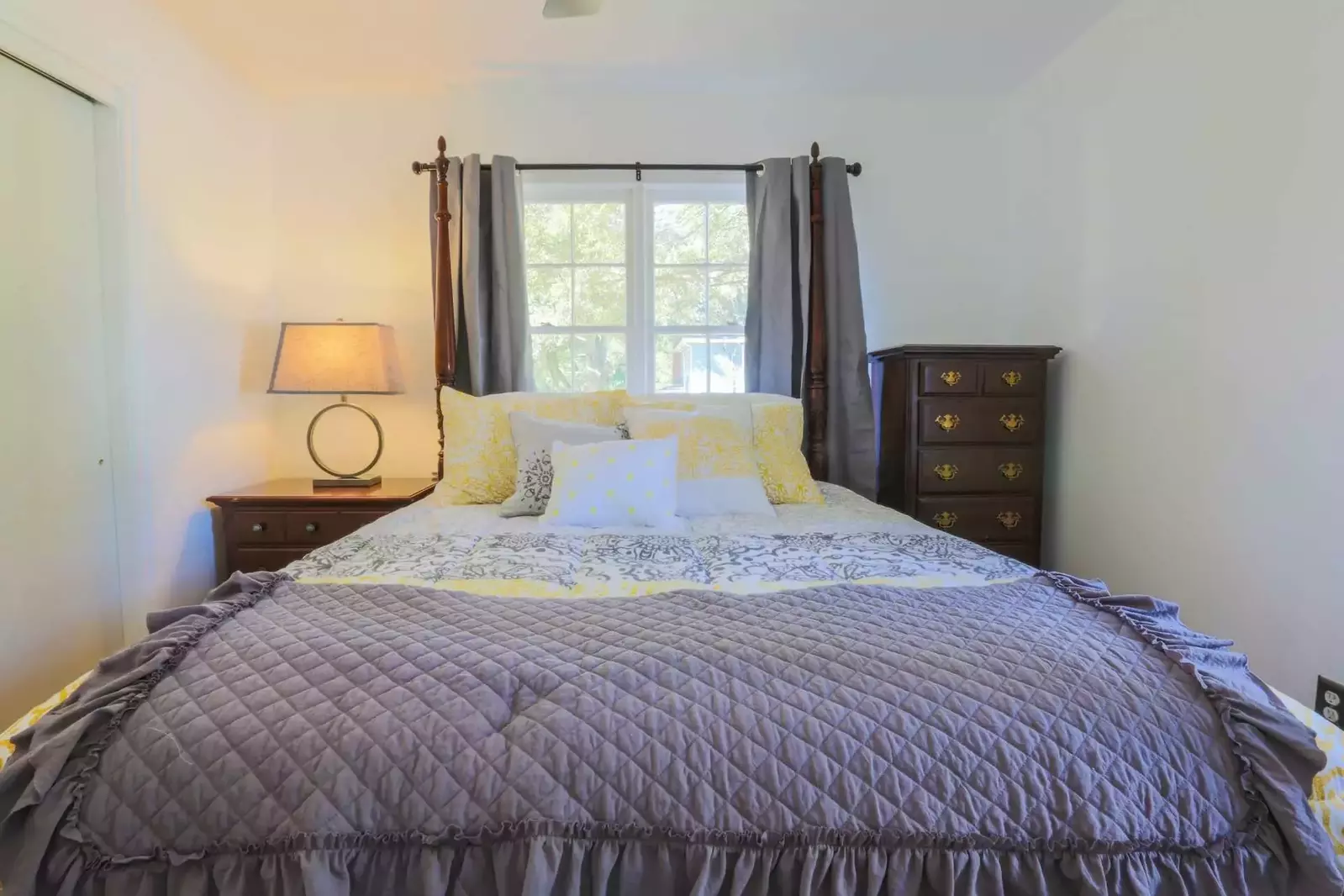 This bedroom features a queen size poster bed, dresser and nightstand with reading lamp.