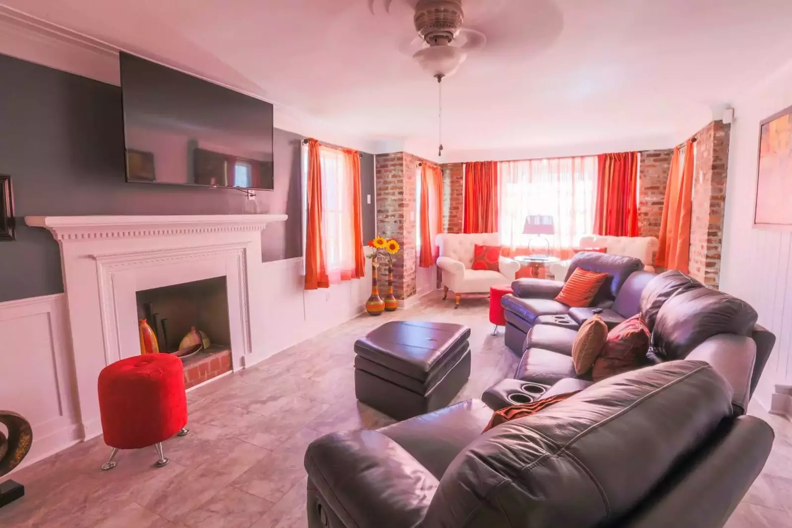 The family room has a mounted large screen TV, comfortable seating and a ceiling fan.