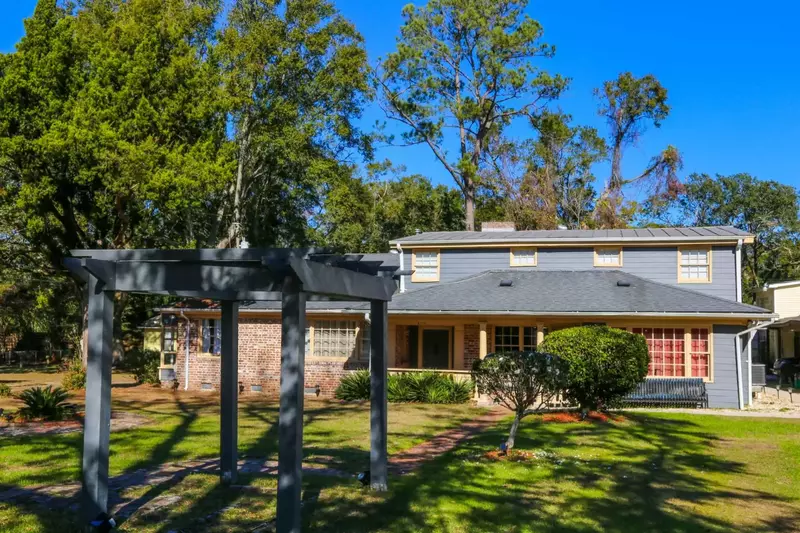 There is a pergola in the middle of the large front yard.
