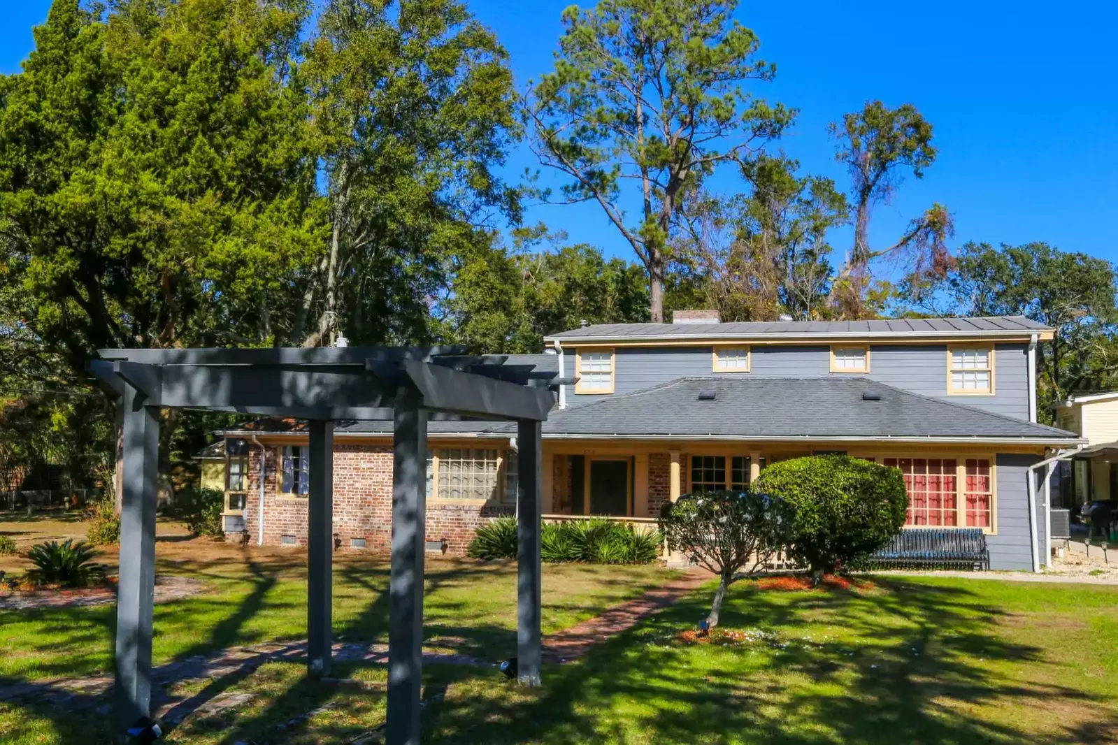 There is a pergola in the middle of the large front yard.