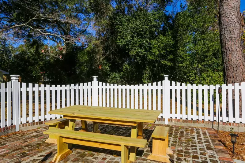 There is a brick patio and picnic table in the backyard.