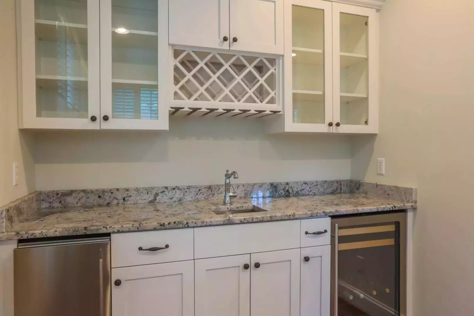 The wet bar adjacent to the dining room features built-in cabinetry and a wine refrigerator.