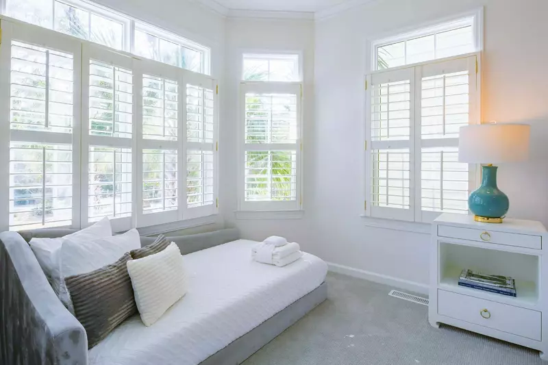 The master suite has a day bed and multiple windows looking out the front of the home.