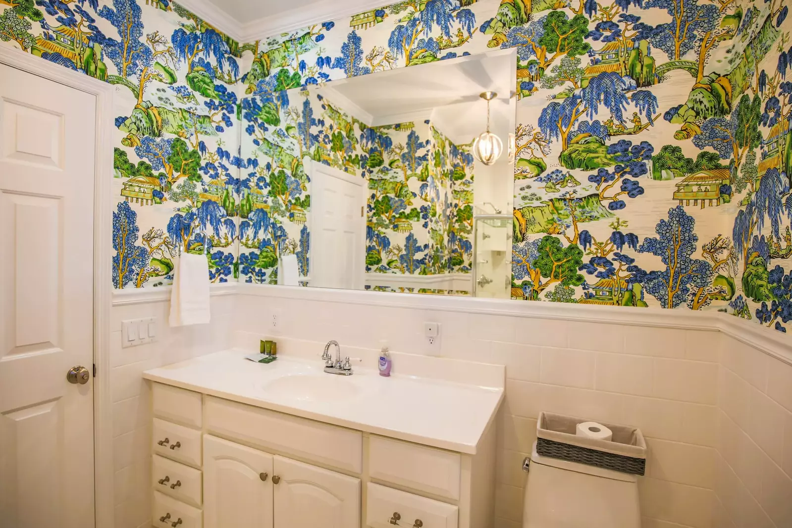 The en suite bathroom within the master suite has tiled walls, gorgeous wallpaper and a spacious vanity.