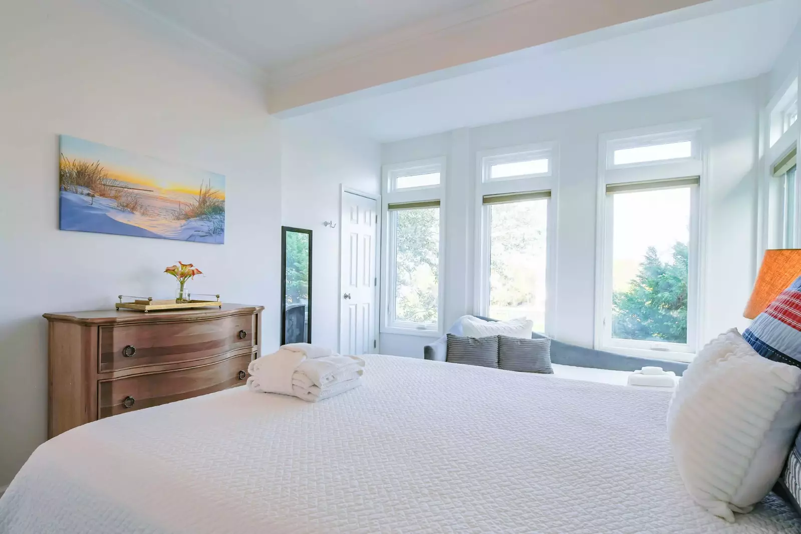 This guest bedroom features a queen bed, dresser, day bed and multiple windows.