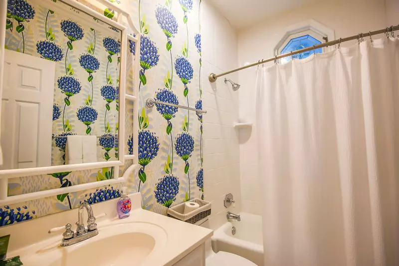 This bathroom, which is located off the 2nd floor hallway, has a tiled shower/tub combo.