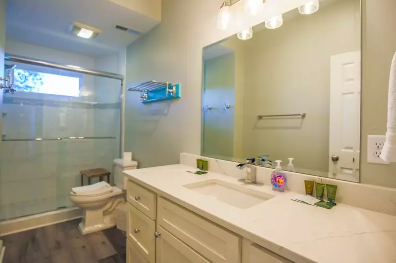 This spacious bathroom with a tiled walk-in shower and large vanity is located on the ground floor.
