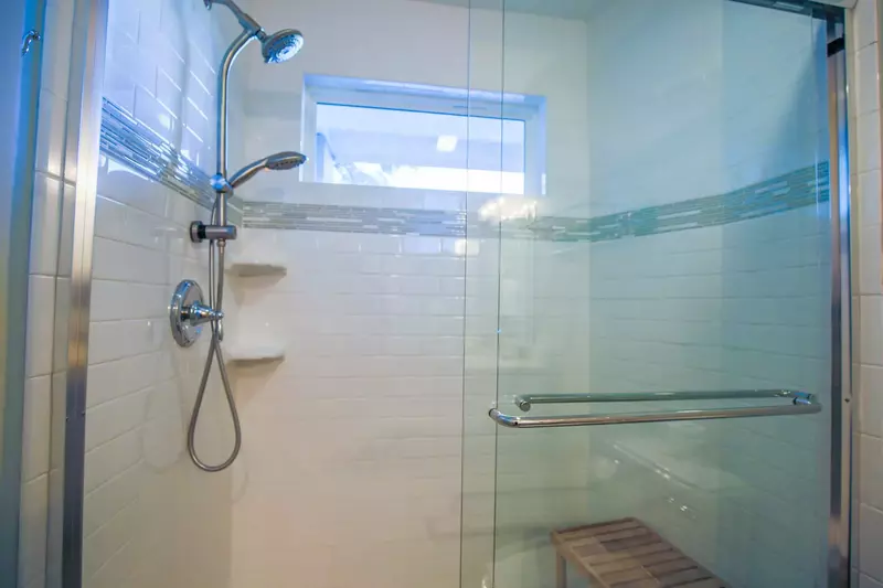 The tiled, walk-in shower has two shower heads and a bench.