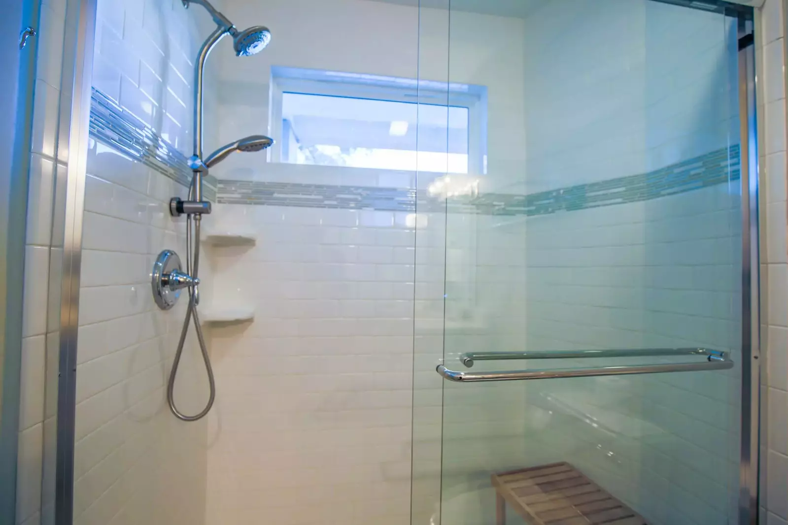 The tiled, walk-in shower has two shower heads and a bench.