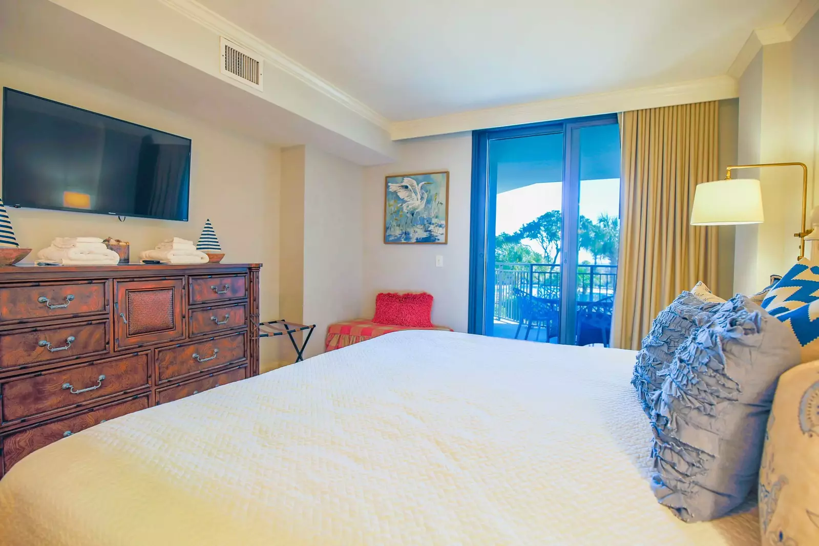 The master bedroom also features a dresser and wall-mounted smart TV.
