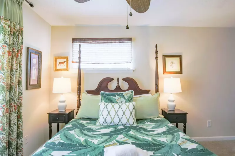 The home's master suite features a queen bed, nightstands with reading lamps and a ceiling fan.