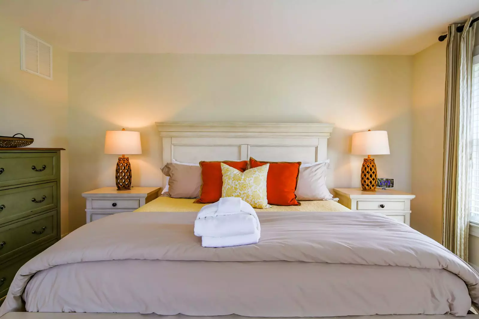 The third floor master suite has a king bed, night stands with reading lamps and two dressers.