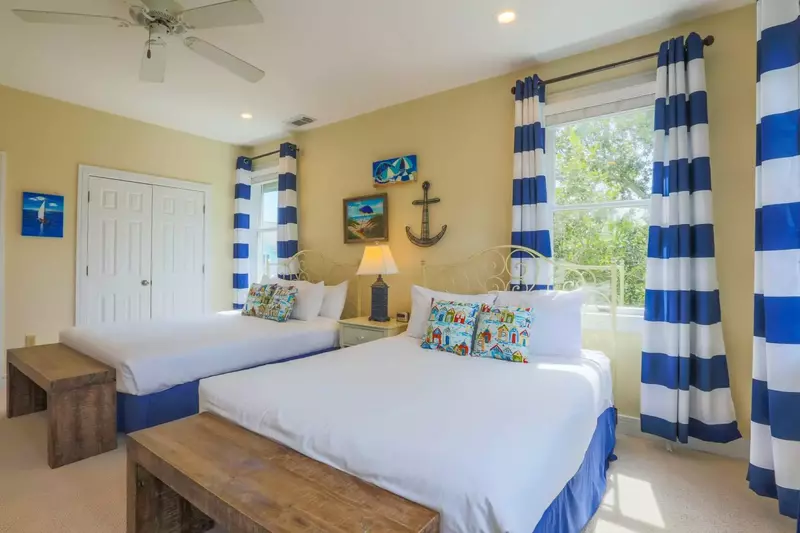 This queen suite has two queen beds, a night stand with reading lamp and a ceiling fan.