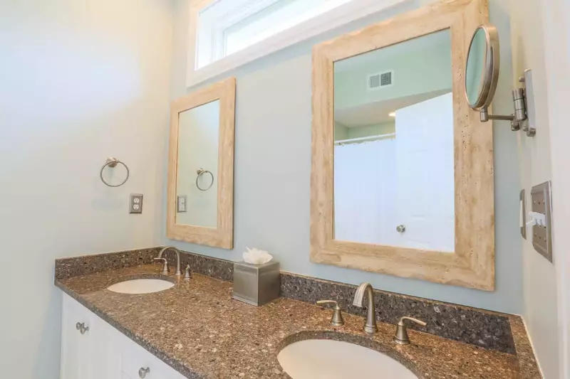 This en suite bathroom also features a double sink vanity with granite countertops and a shower/tub combo.