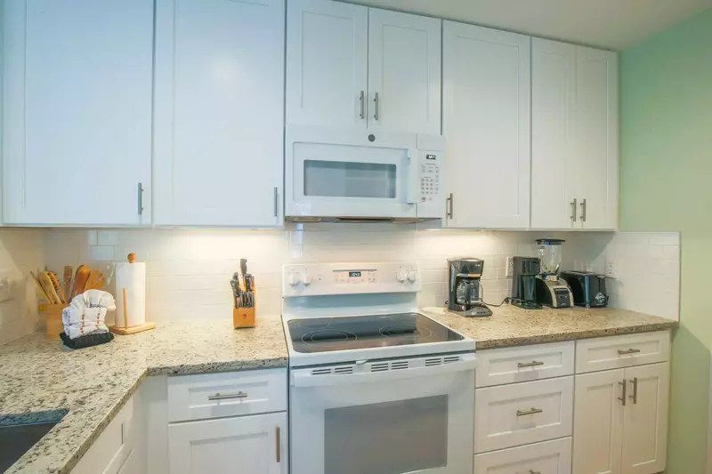 The kitchen is well stocked with clean, white appliances.
