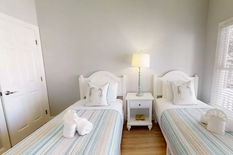 This bedroom features two twin beds and a night stand with a reading lamp.