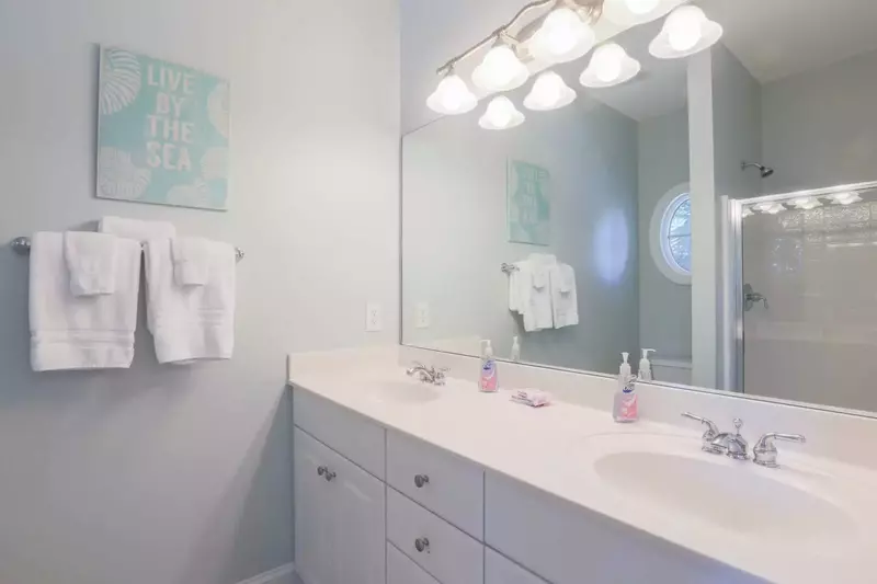 This en suite bathroom has a double sink vanity and tiled walk-in shower.
