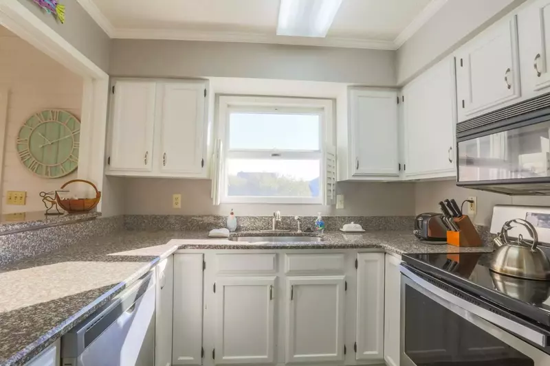 The kitchen features white cabinetry, stainless steel appliances and views of the lagoon behind the cottage.