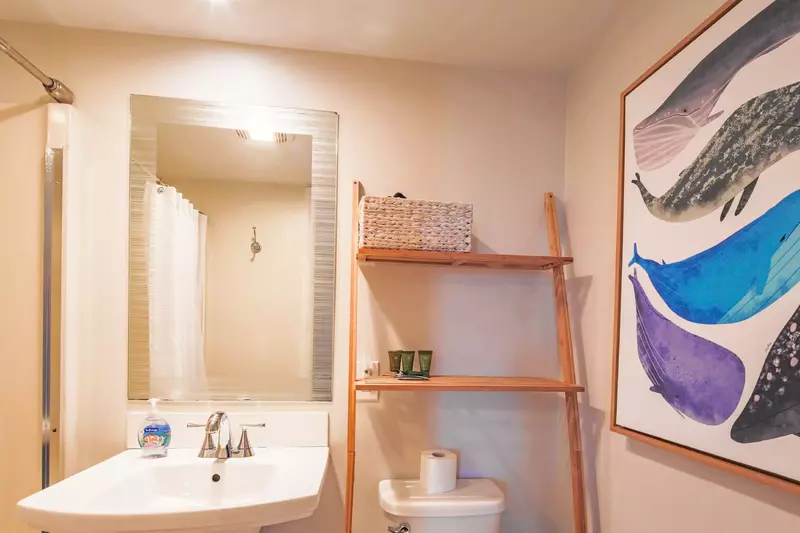 The en suite bathroom has a pedestal vanity and set of shelves.