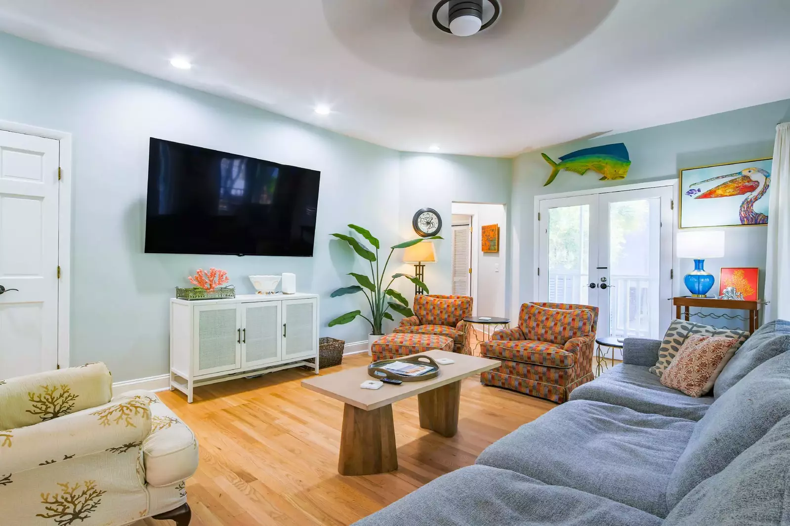 The living room features a spacious seating area, wall-mounted TV and vibrant artwork.