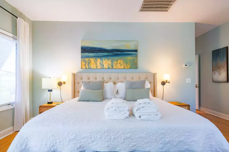 The primary suite features a king bed, nightstands and wall-mounted sconces.