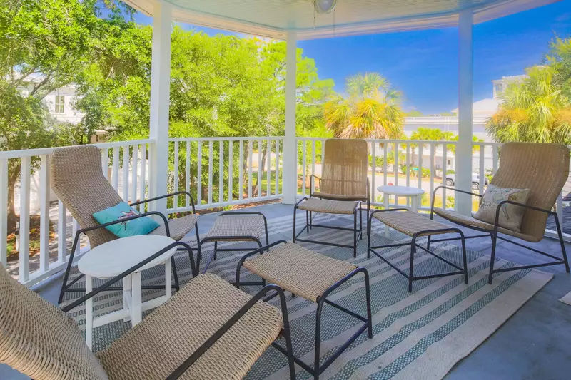 The private covered balcony off of the primary suite features a seating area with a ceiling fan.