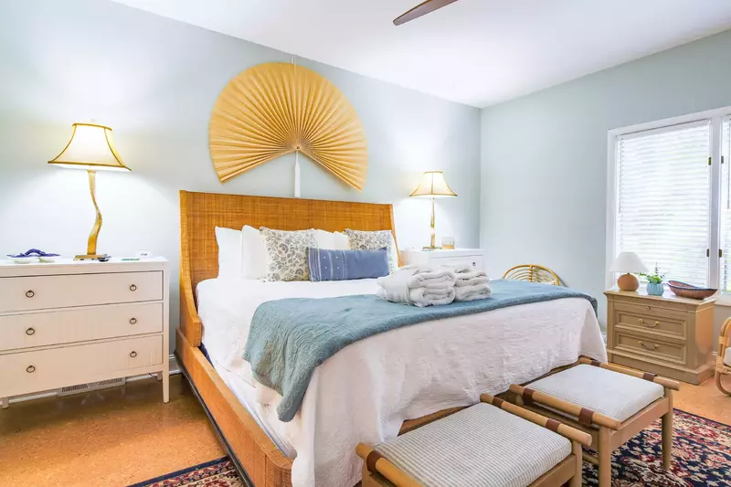 The guest suite features a king bed, night stands with reading lamps and bench seating.
