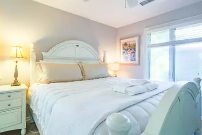 The master suite features a king bed, night stands with reading lamps and a ceiling fan.