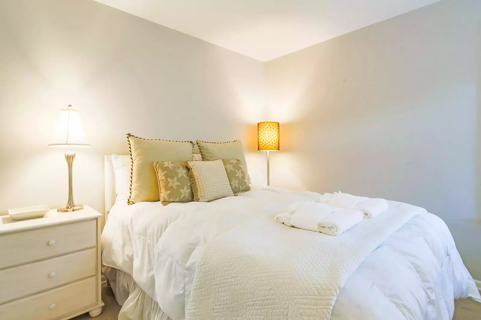 The guest bedroom features a queen bedroom, night stand and reading lamps.