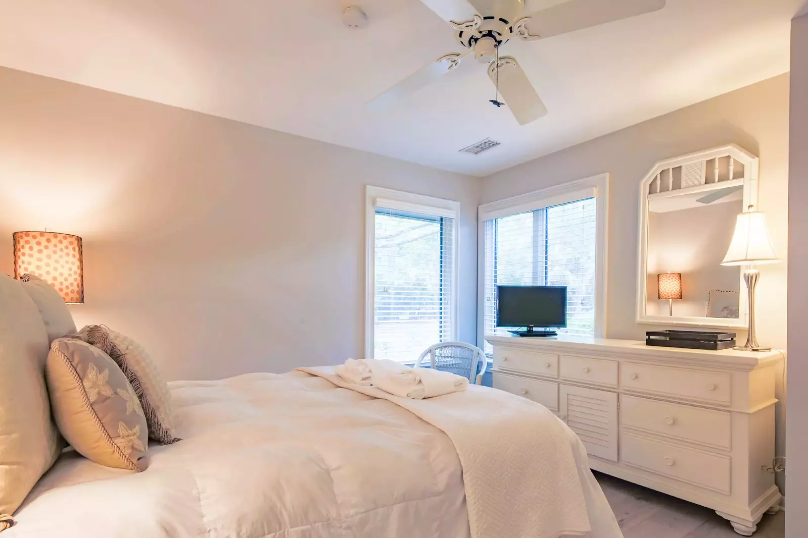 The guest bedroom also features a dresser, small TV and ceiling fan.