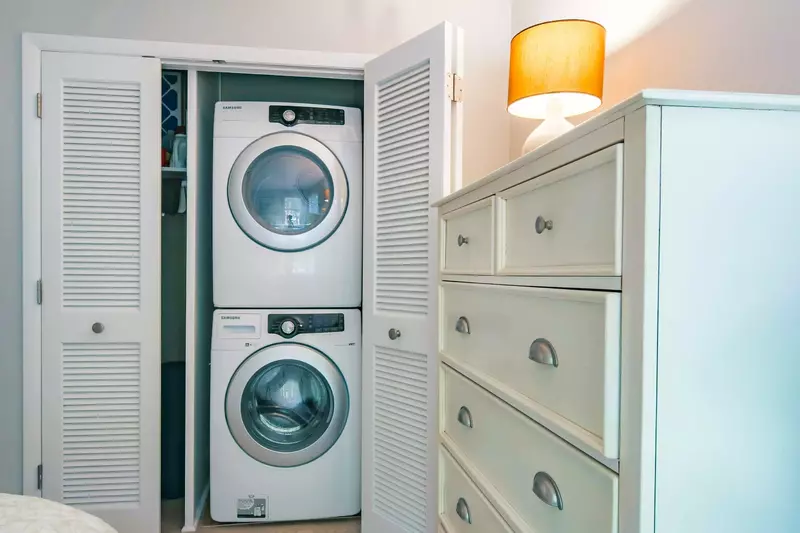 There is a full-sized washing machine and dryer stacked in the guest bedroom closet.