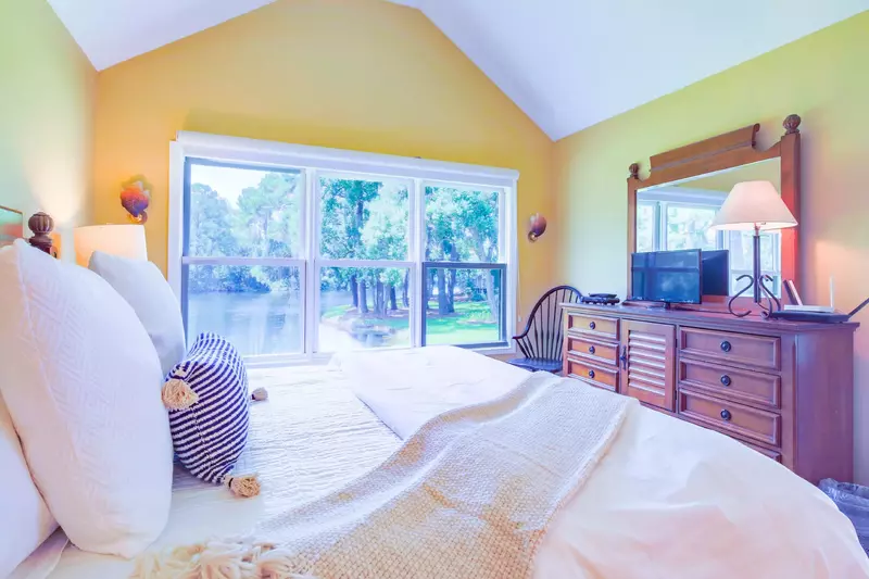 The primary suite also has vaulted ceilings, a dresser with TV and a chair.