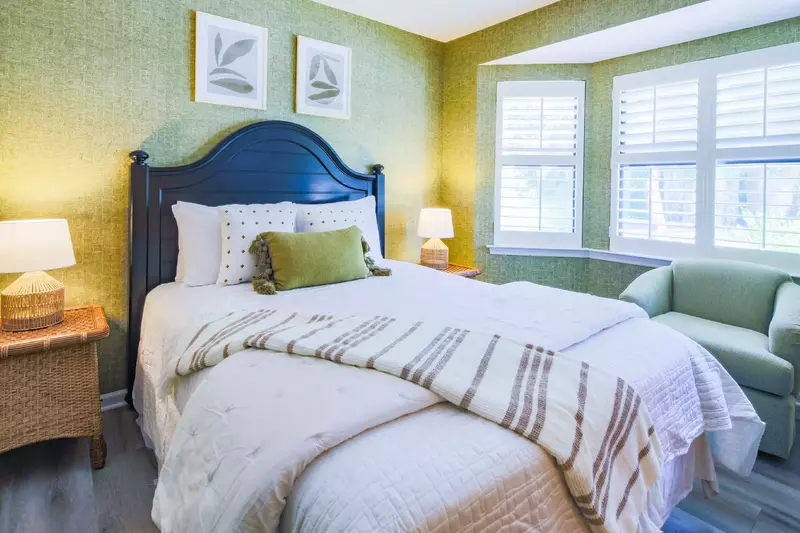 The guest bedroom features a queen bed, night stands with reading lamps and an arm chair.