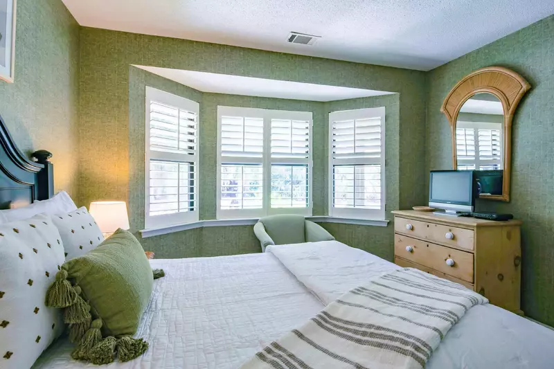 The guest bedroom also has a dresser, wall-mounted mirror and small TV.