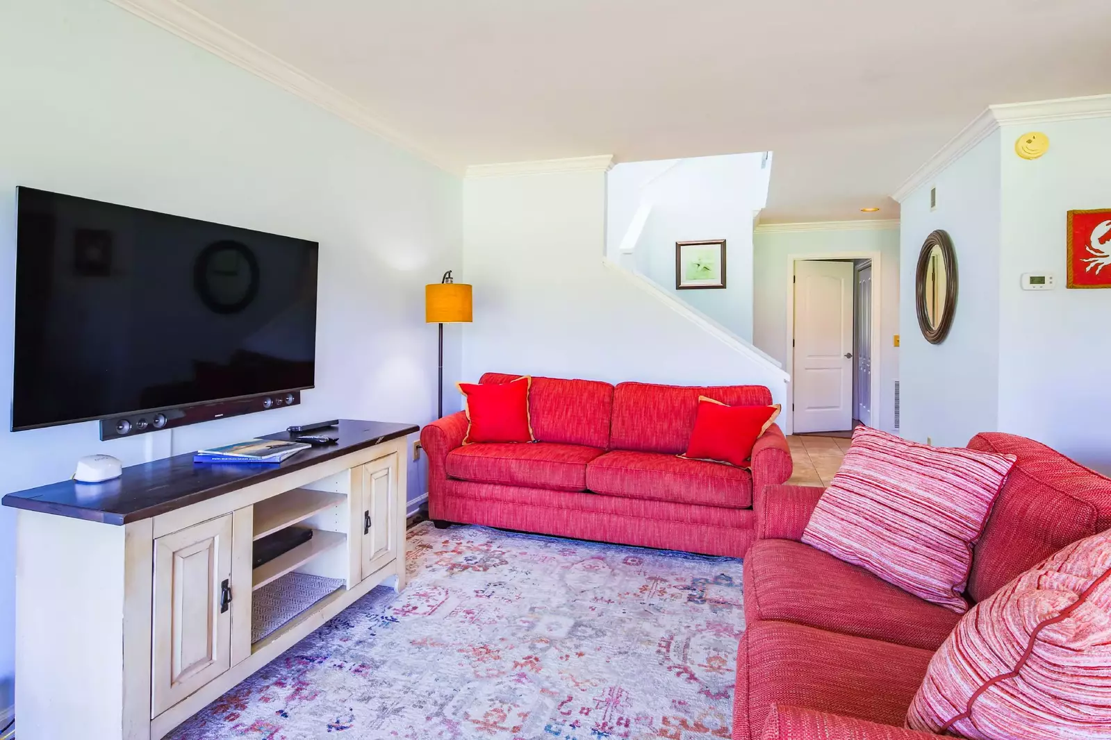 The living room features a sofa, love seat and wall-mounted smart TV.