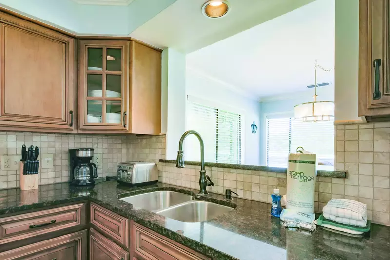 The renovated kitchen features granite counters, brown cabinets and a tiled backsplash.