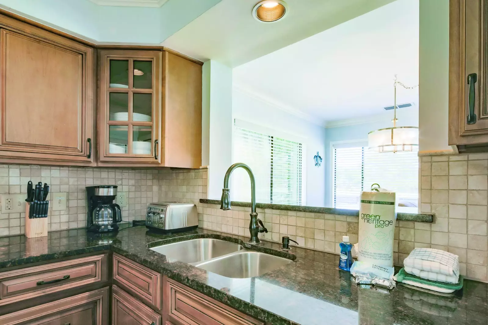 The renovated kitchen features granite counters, brown cabinets and a tiled backsplash.