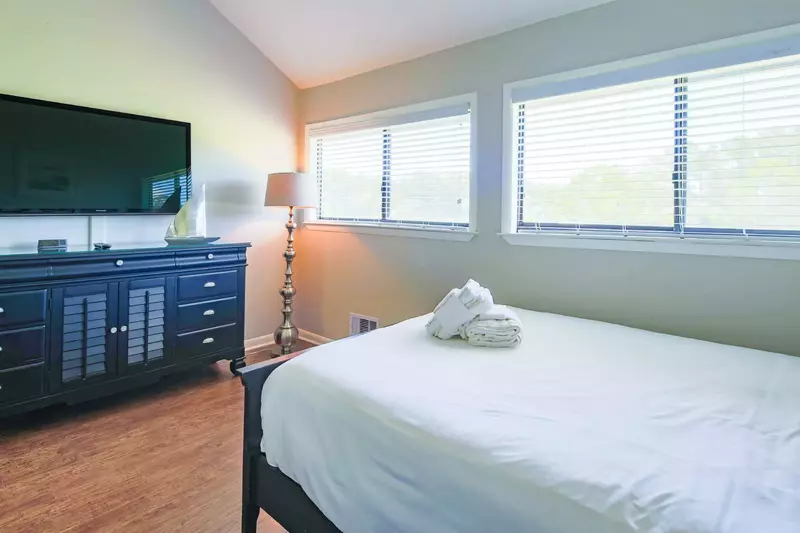 The master suite also features a dresser and wall-mounted smart TV.