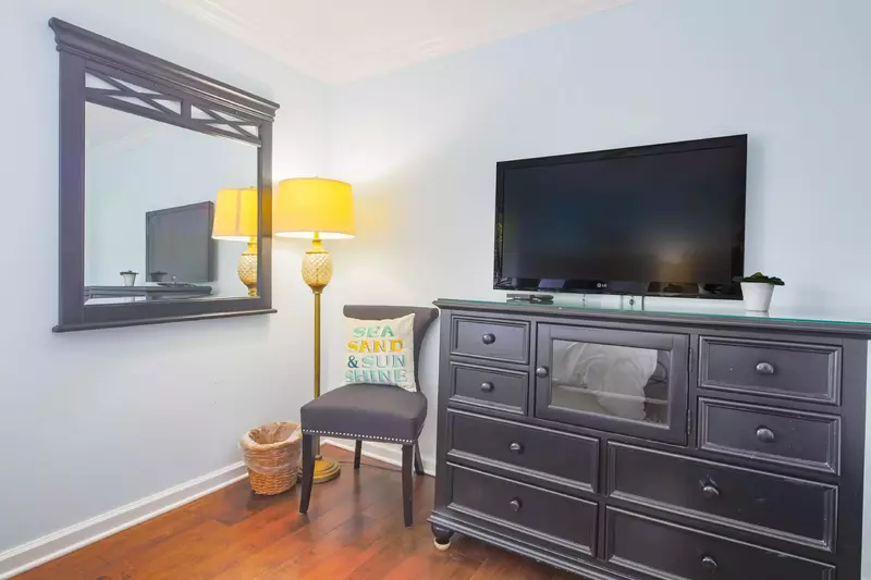 The guest bedroom also features a dresser with a wall-mounted smart TV.