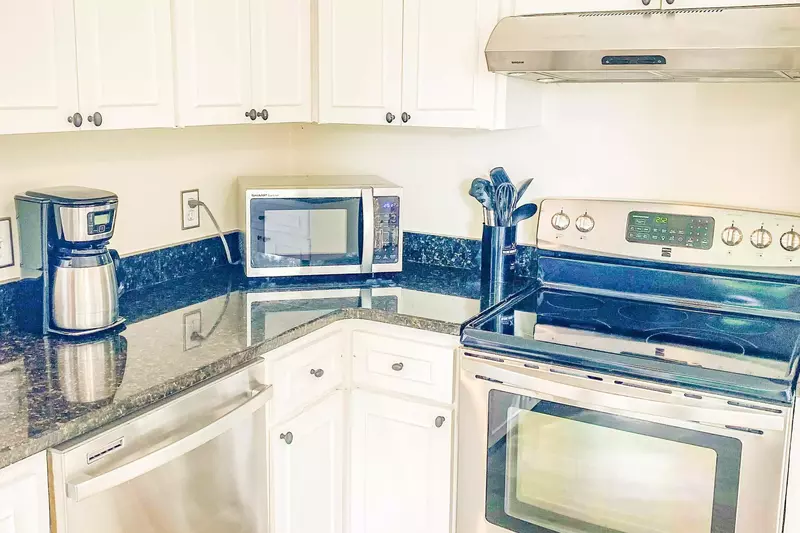 The kitchen features an electric range with hood, a microwave and a drip coffee maker.