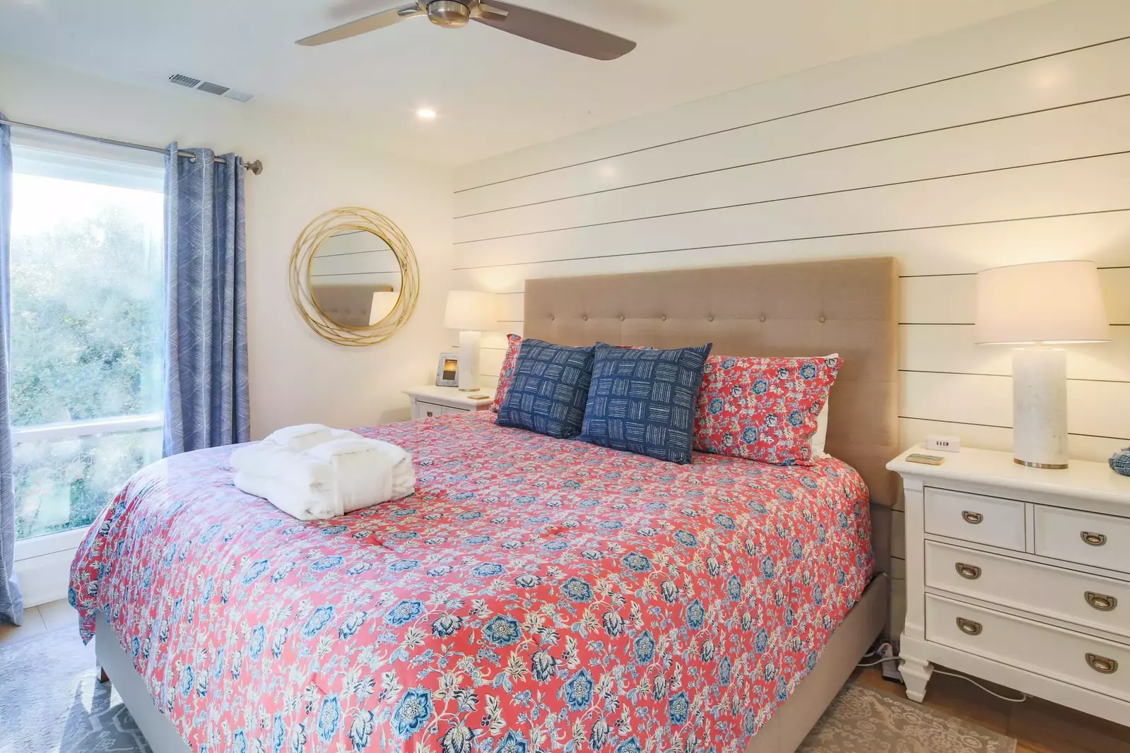 The master suite features a king bed, night stands with reading lamps and shiplap walls.