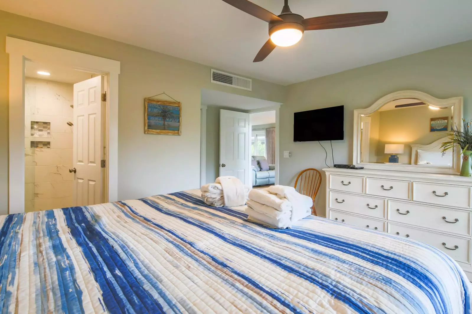 The master suite features a dresser, ceiling fan, TV and en suite bathroom.