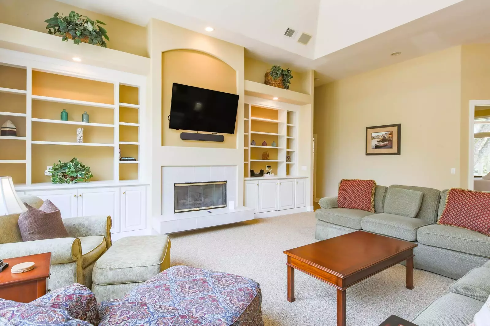 The living room features a spacious seating area, built-in bookshelves and a wall-mounted TV.