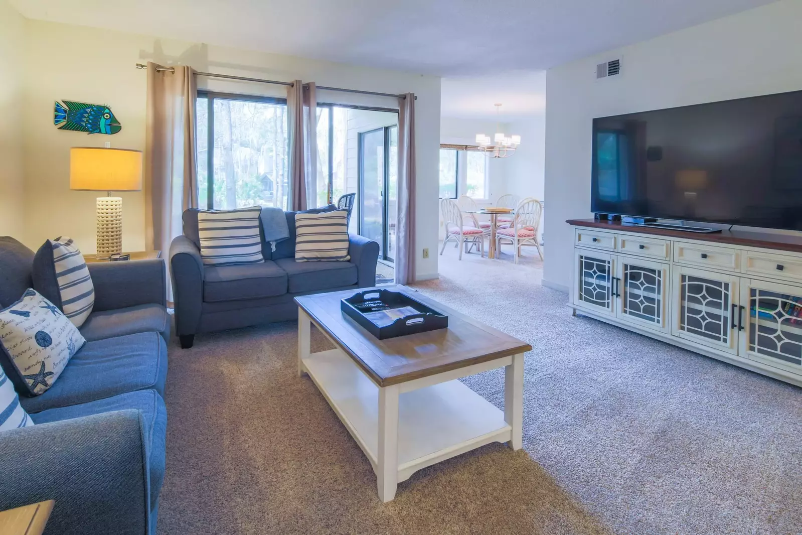 The living room has a large screen TV and connects to both the covered patio and the dining room.