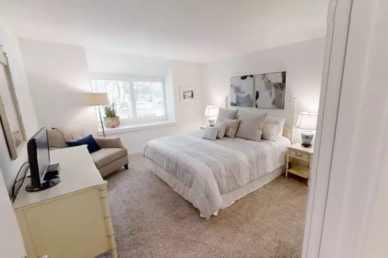 The master suite features a king bed, night stands with reading lamps and an arm chair.
