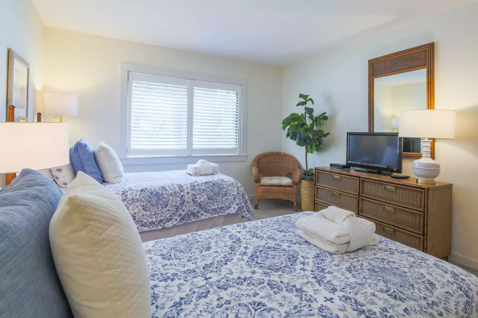 The guest bedroom also features a dresser, small TV and an arm chair.