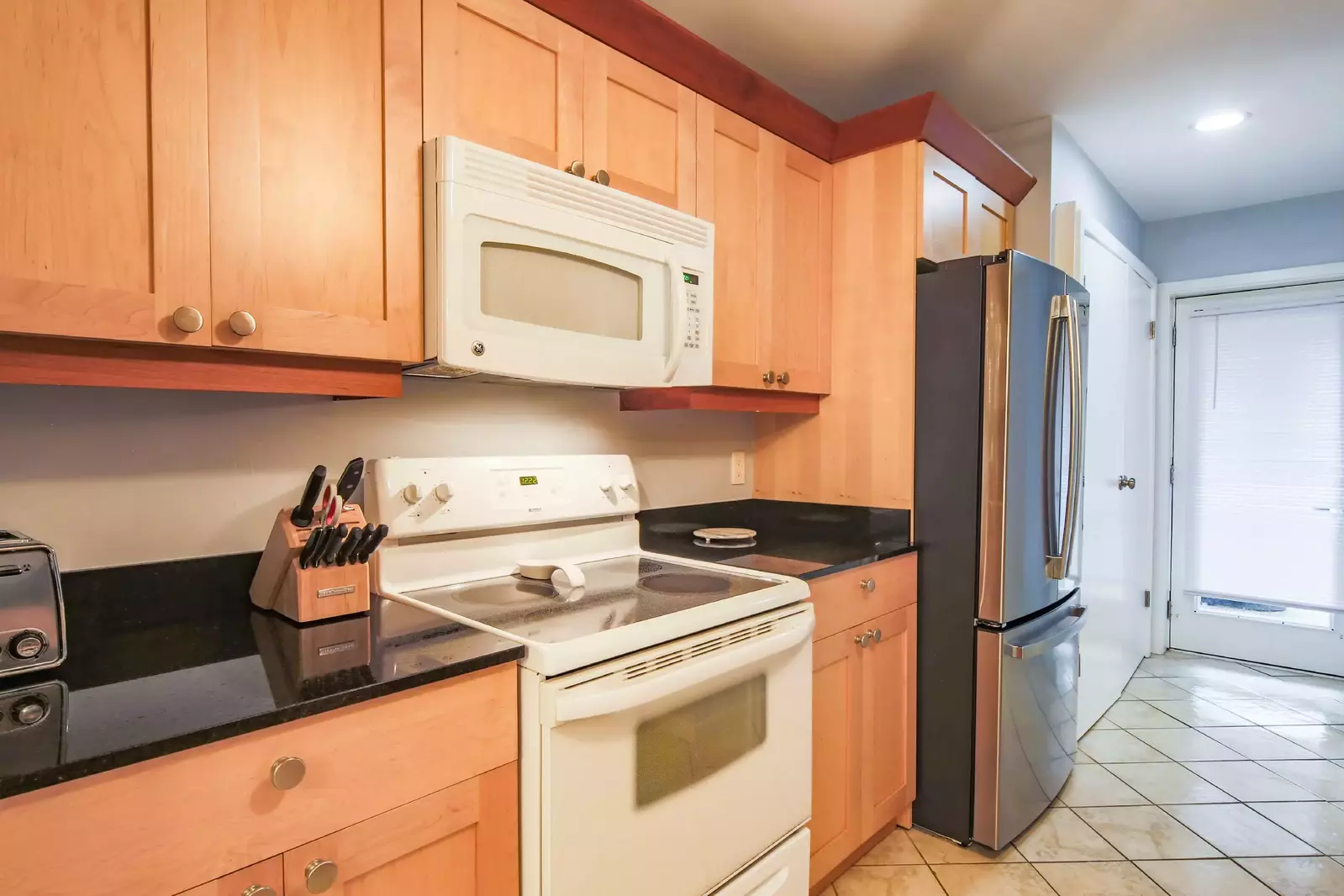 The kitchen features a refrigerator, range, microwave, toaster and more.